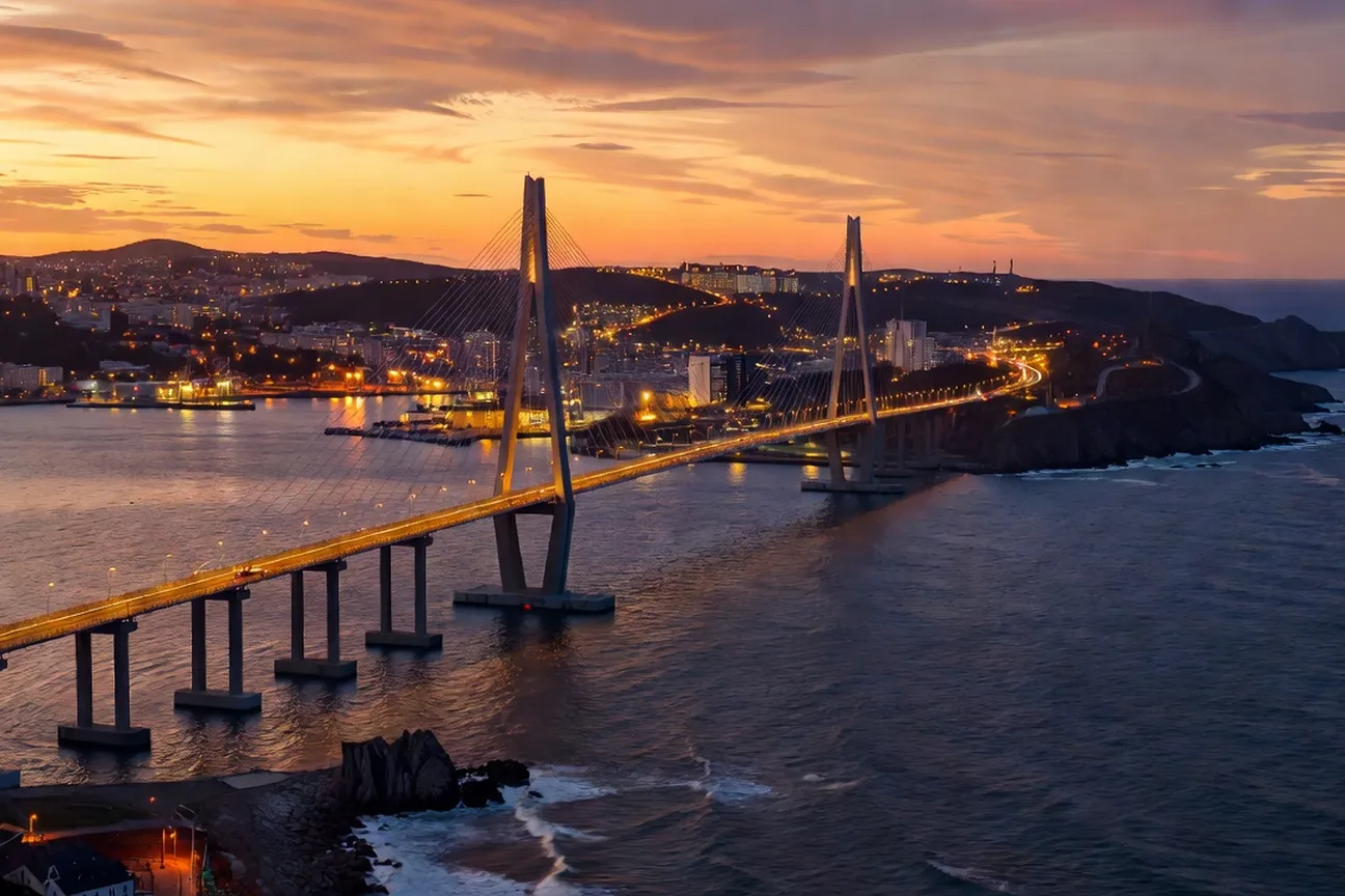 Vue panoramique de la baie d'or de Vladivostok au coucher du soleil avec le pont haubané du Détroit du Bosphore oriental illuminé et les collines portuaires en arrière-plan